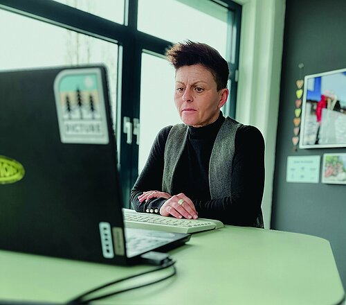 Isabell Janoth, Inhaberin von Buzil, sitzt an einem Schreibtisch und blickt in den Bildschirm eines Laptops